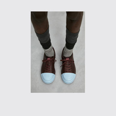 A model wearing Junction Runner Burgundy leather sneakers
