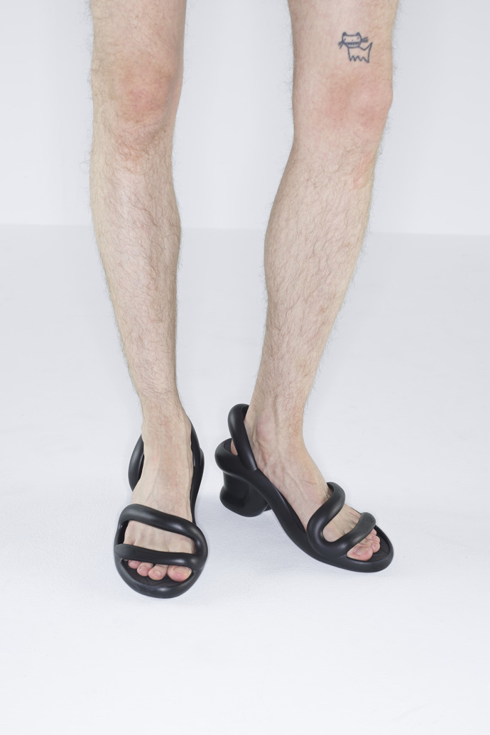 A model wearing Kobarah Black unisex sandals