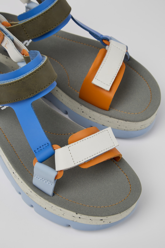 Close-up view of Oruga Up Blue, orange, and white leather sandals for women