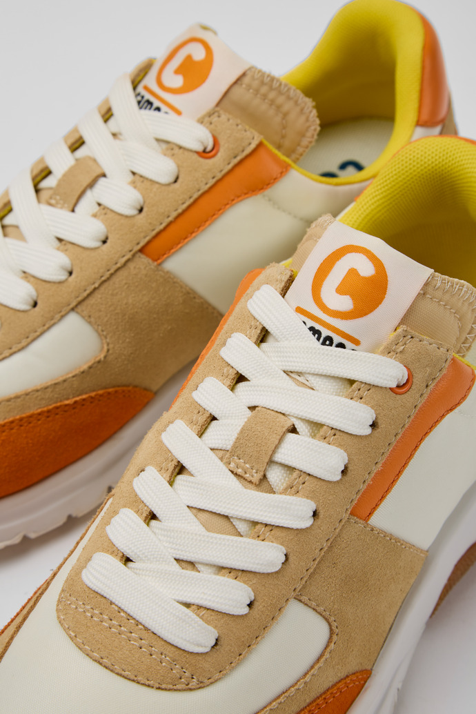 Close-up view of Drift White, beige, and orange nubuck sneakers for women