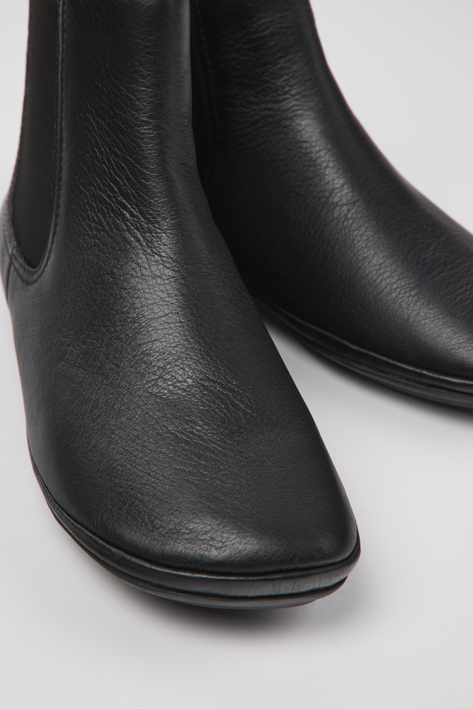 Close-up view of Right Black leather ankle boots