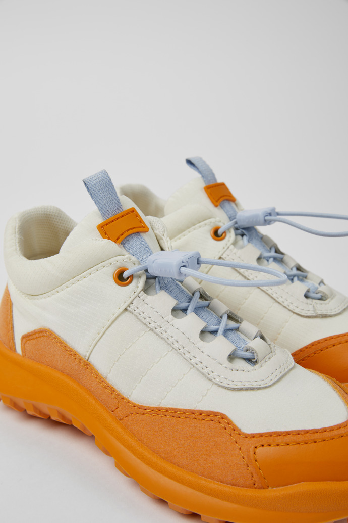 Close-up view of CRCLR White and orange sneakers for kids