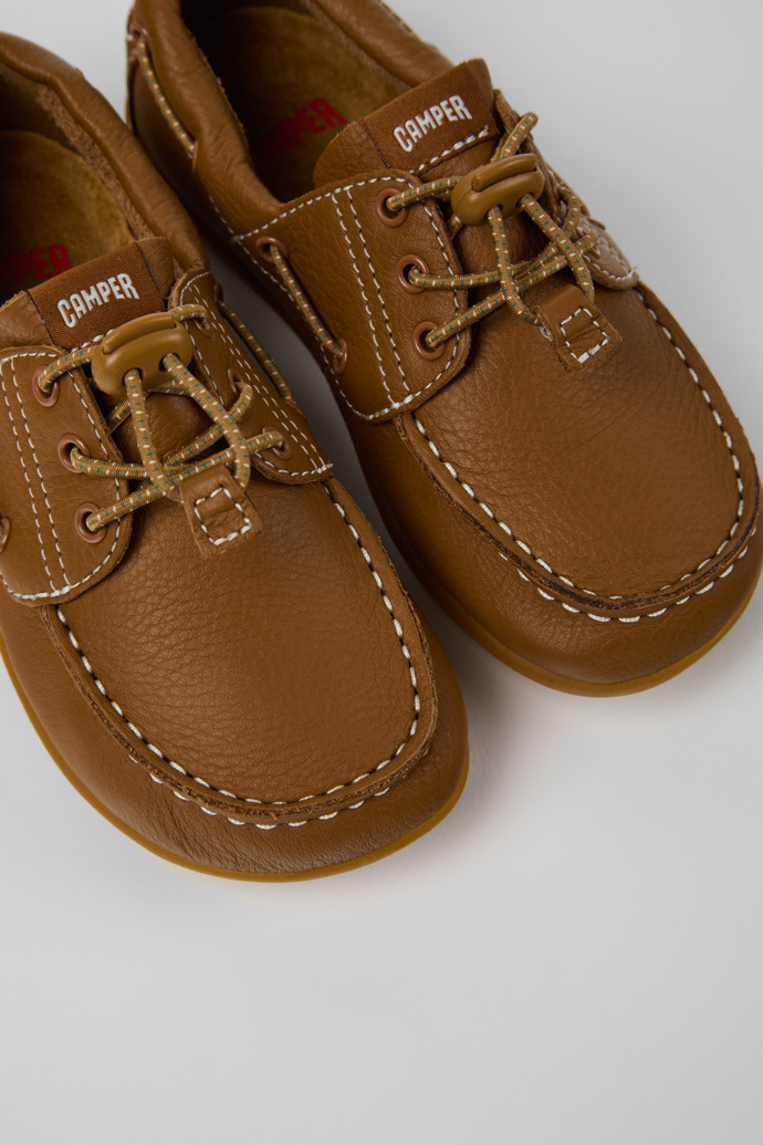 Peu Chaussures bateau en cuir marron pour enfants.