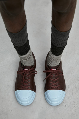 A model wearing Junction Runner Burgundy leather sneakers